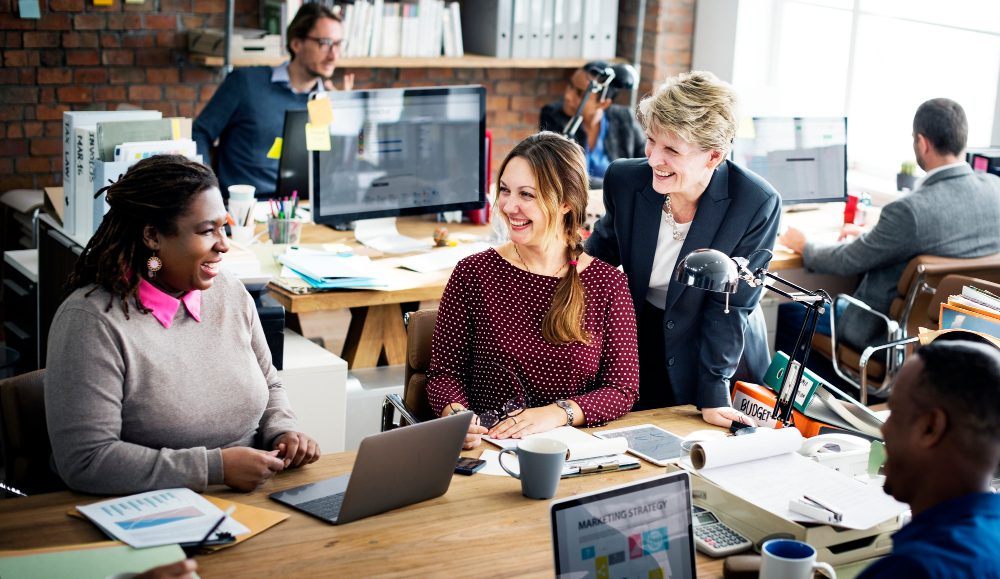 Colleagues in an office setting working happily together to represent SharePoint Modern Workplace