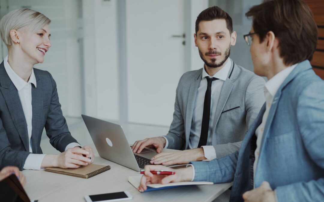 Business professionals in a meeting with laptops and notebooks, discussing strategy.